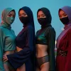 Four women in hijabs and masks stand against a city skyline